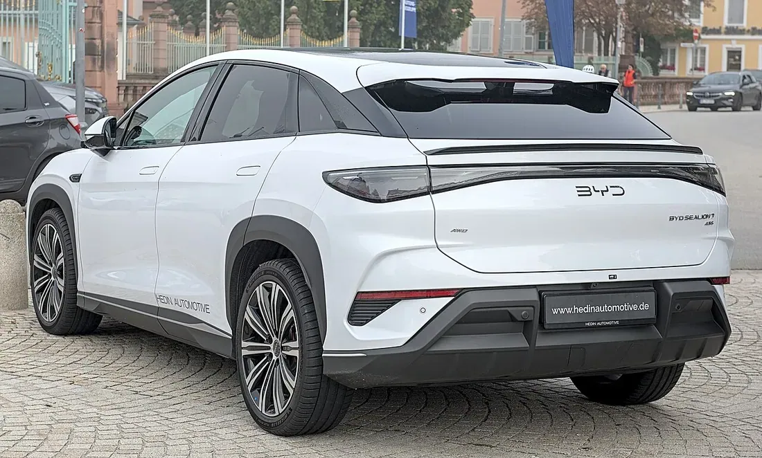 White BYD Sealion 7 electric SUV parked on a city street, rear three-quarter view