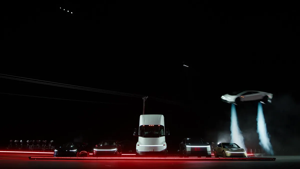 Tesla Roadster hovering beside a Tesla Semi and other Tesla vehicles