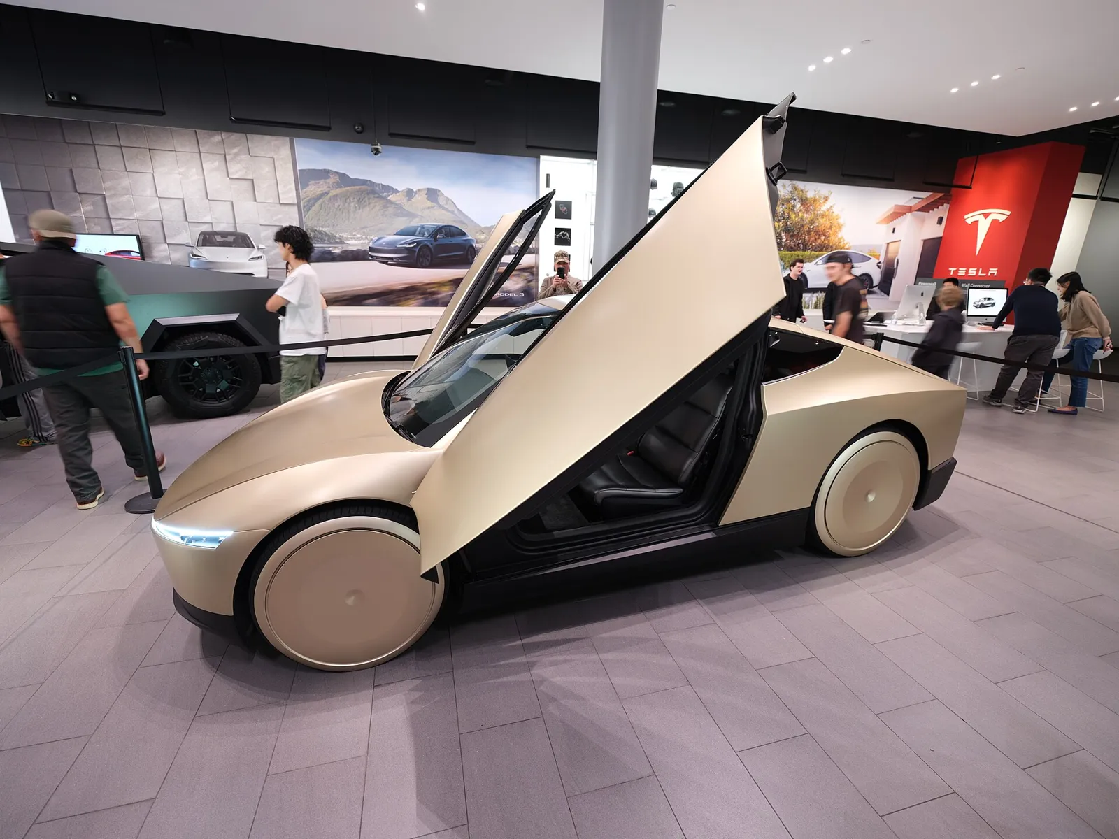 Gold two-seat Tesla Cybercab with butterfly doors on display