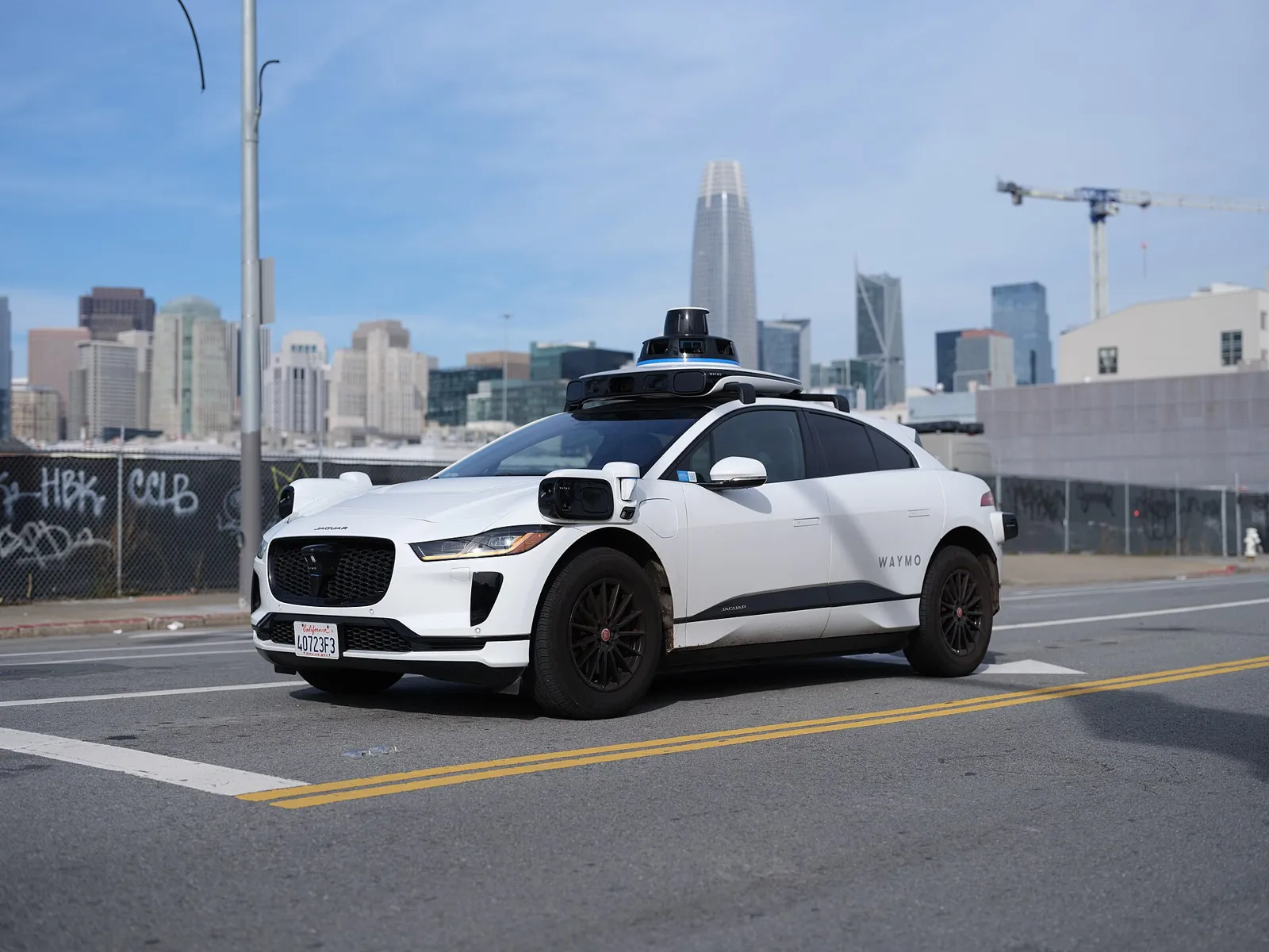 White Waymo Jaguar I-Pace robotaxi with roof sensors on a San Francisco street